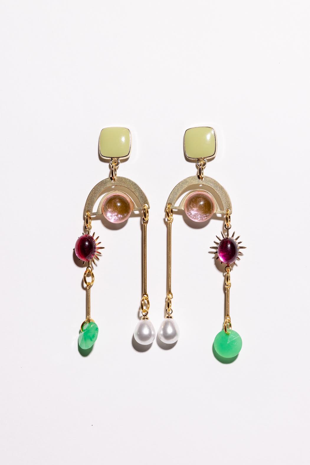 Pair of gold earrings with gemstones and pearls on a white background
