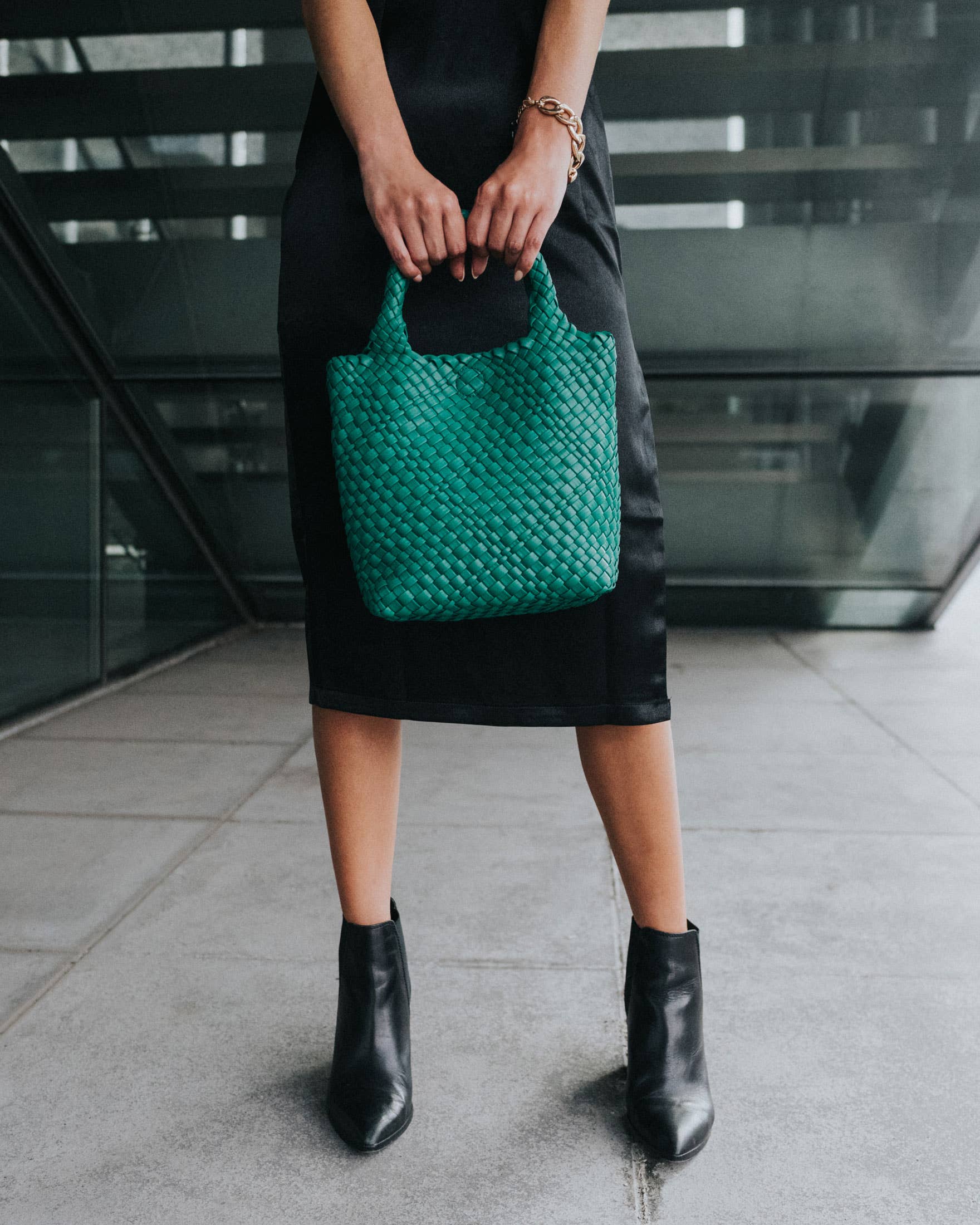 Person holding a green woven handbag in an urban setting, Eloise Woven Small Green Tote Bag Melie Bianco