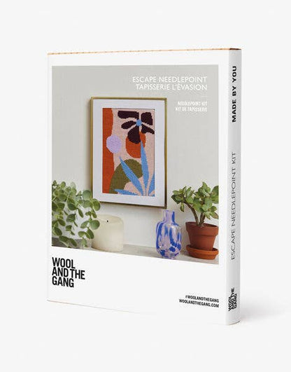 Wool and the Gang needlepoint kit packaging with a framed artwork on a shelf.