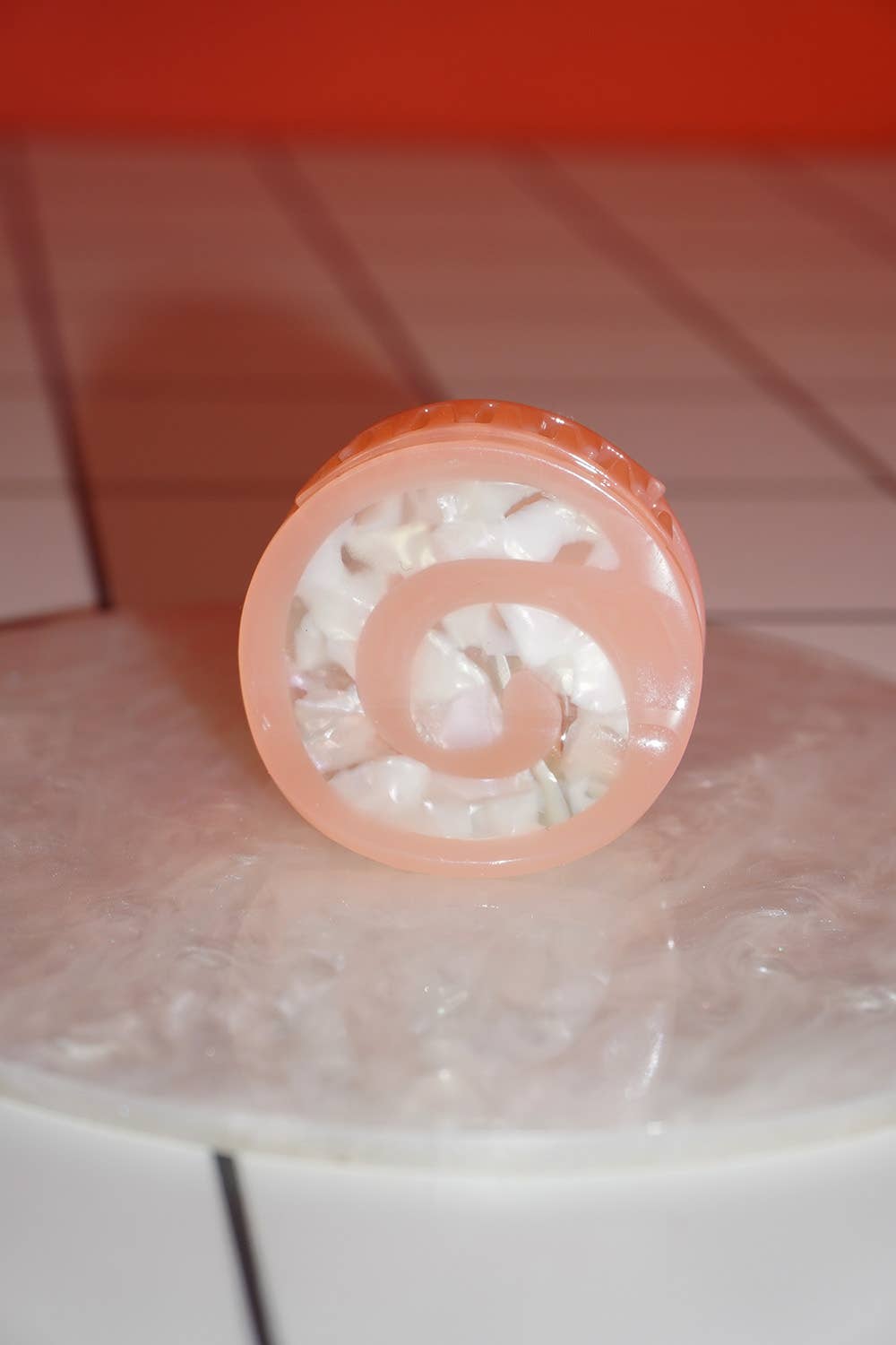 Pink lip balm with a spiral design on a tiled surface
