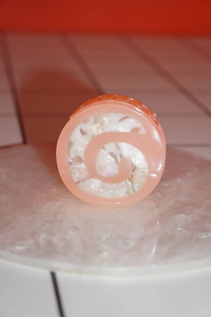 Pink lip balm with a spiral design on a tiled surface