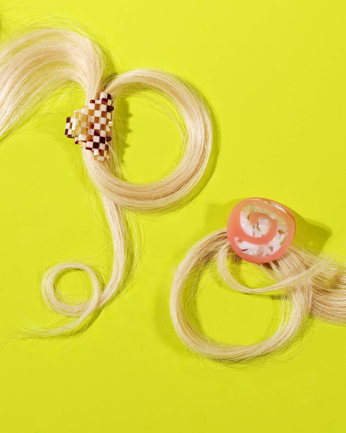 Blonde hair extensions with decorative clips on a bright yellow background