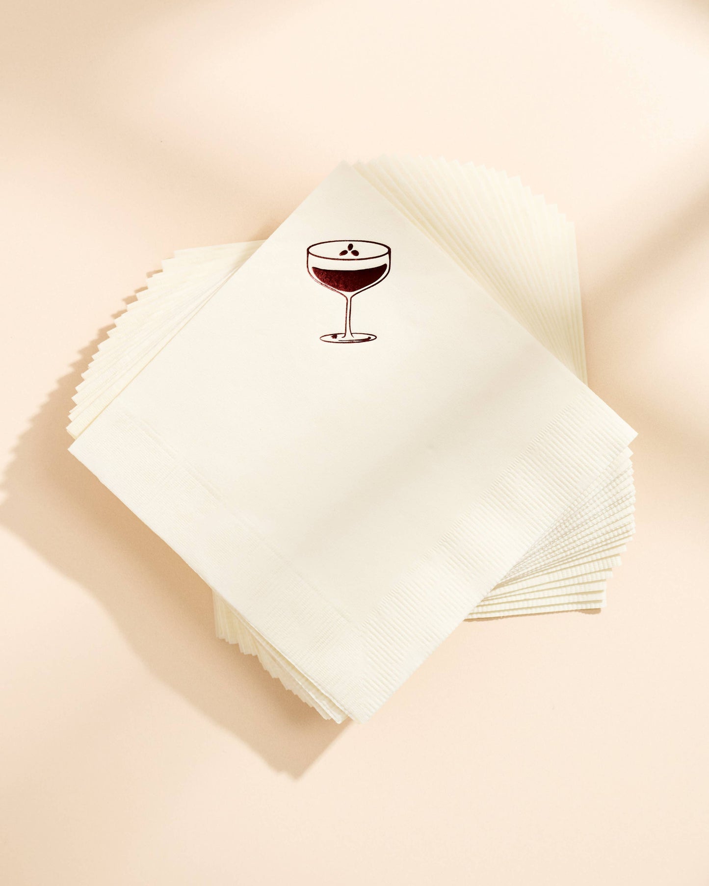 Stack of white napkins with an espresso martini glass design on a beige background