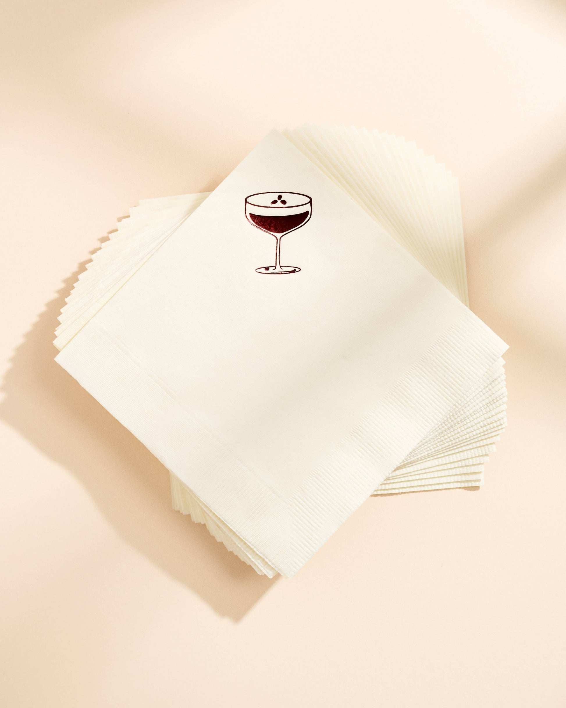 Stack of white napkins with an espresso martini glass design on a beige background