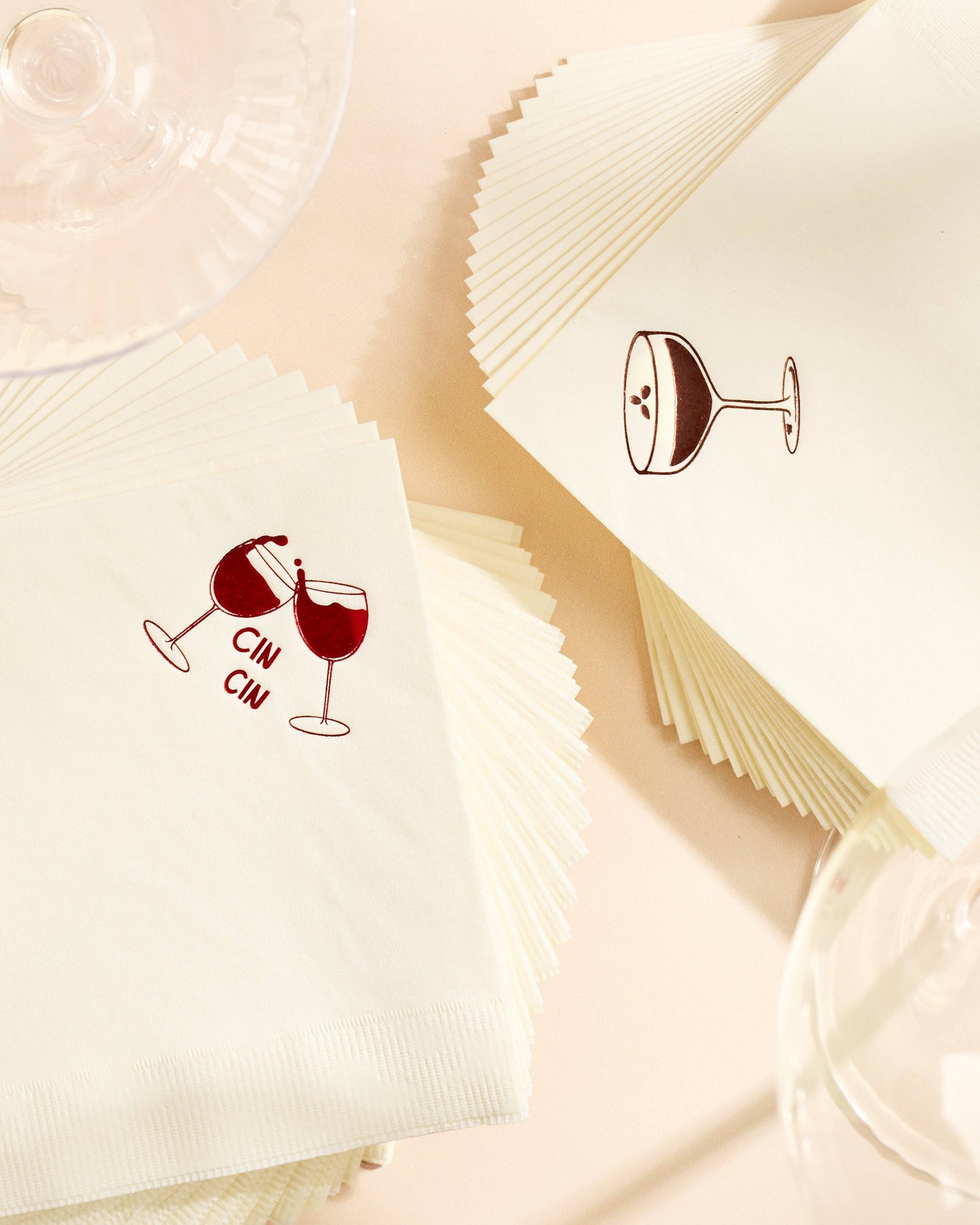 White napkins with red wine glass designs and 'CIN CIN' text on a beige background.