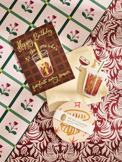 Set of four coasters with a design of a drink and text on a patterned surface