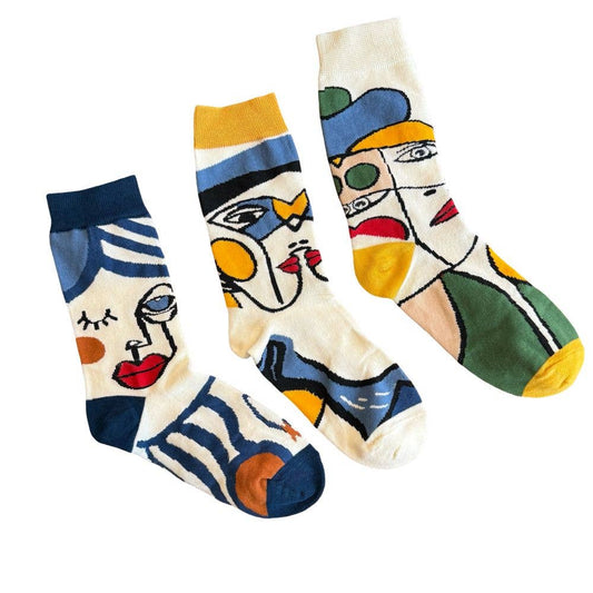 Three crew socks with a colorful, stylized cubist face design, displayed against a solid white background.