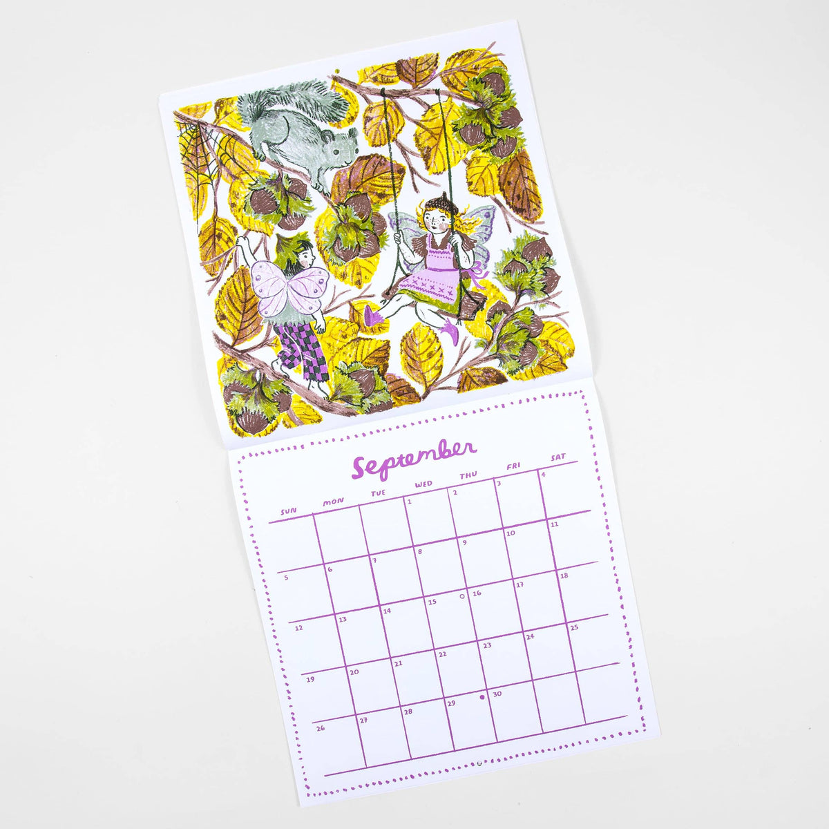 A children's monthly calendar page with a whimsical forest illustration on the front and a September calendar grid below, photographed on a clean white background.