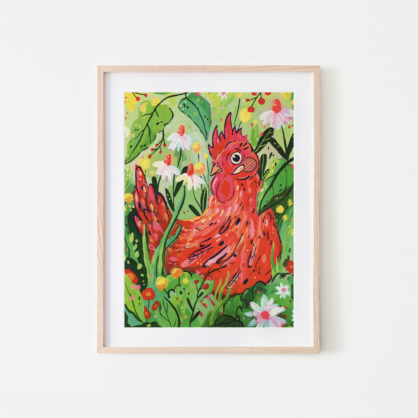 A framed art print featuring a colorful illustration of a red rooster surrounded by green leaves and white flowers, set in a light wood frame against a white wall.