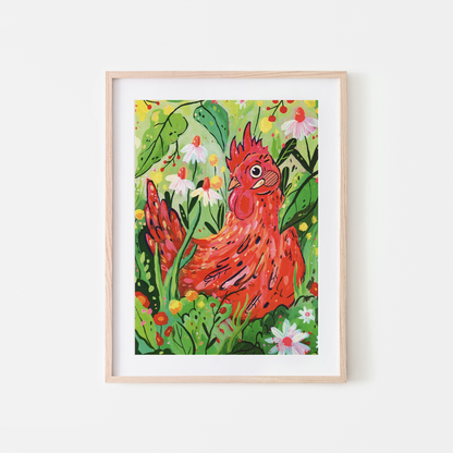 A framed art print featuring a colorful illustration of a red rooster surrounded by green leaves and white flowers, set in a light wood frame against a white wall.