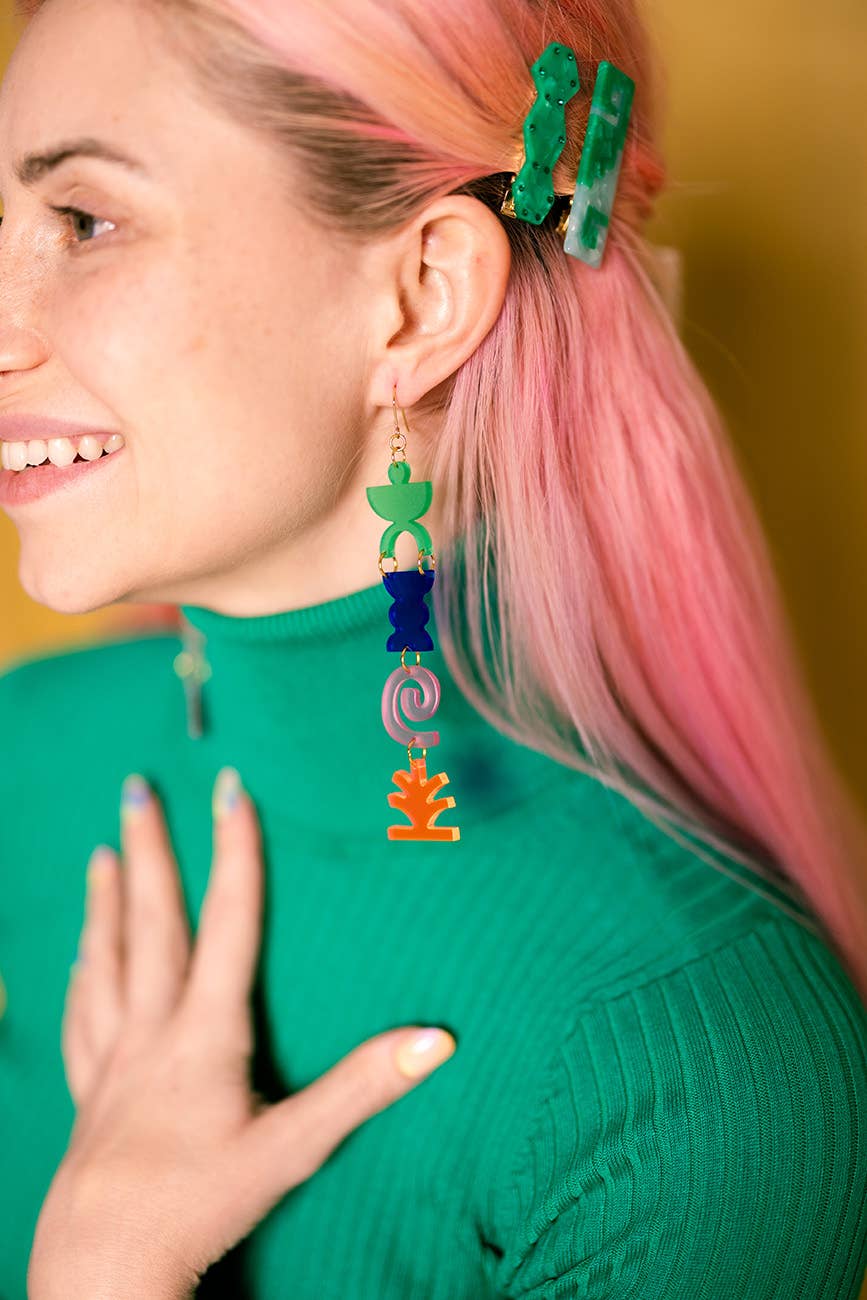 Person wearing colorful earrings with a blurred background