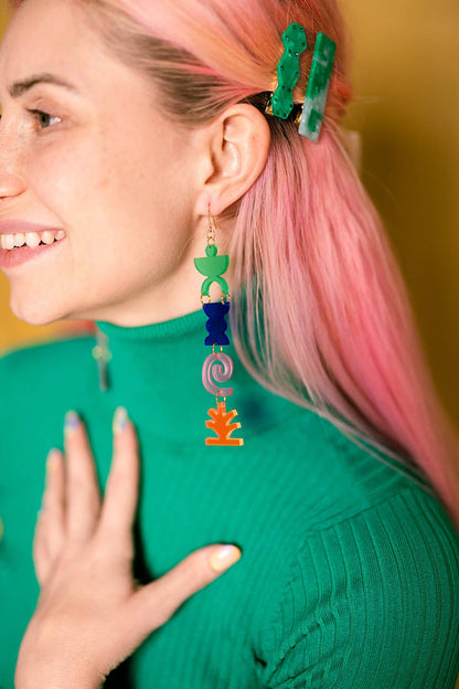 Person wearing colorful earrings with a blurred background