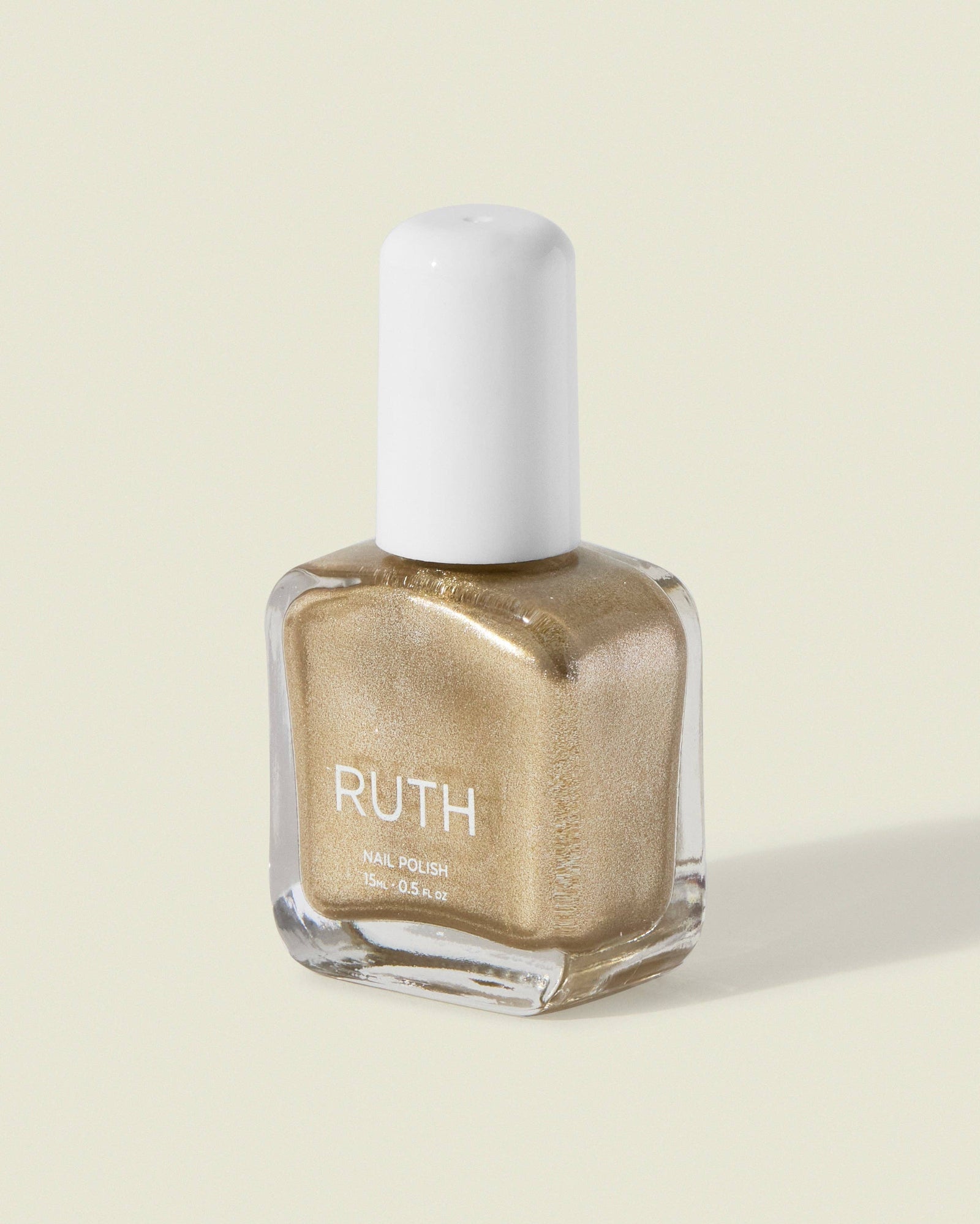 Nail polish bottle with 'RUTH' branding on a beige background, Fizzy Silver Gold Nail Polish