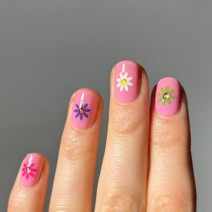 Nails with pink polish and floral designs on a gray background
