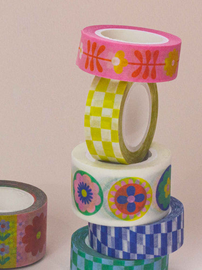 Stack of colorful washi tape rolls with floral and checkered patterns on a beige background.