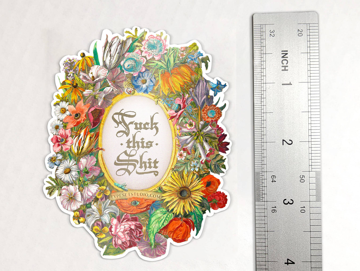 Decorative sticker with floral design and text next to a ruler for scale on a white background