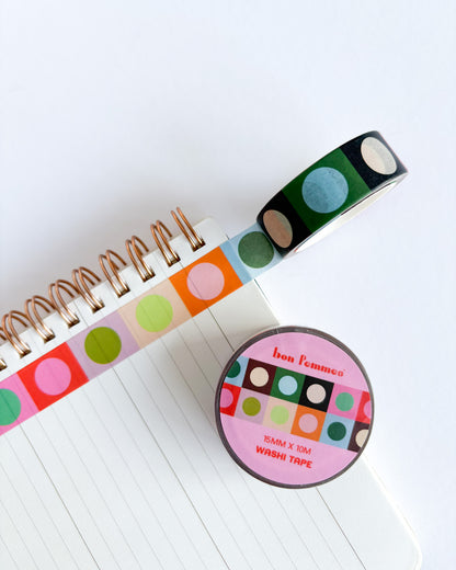 A roll of colorful washi tape with green, blue, pink, orange, and beige polka dots on a white lined notebook, alongside the round pink branded label of Fun Flemming Washi Tape.