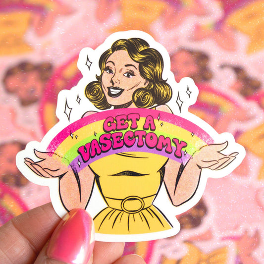 A die-cut sticker featuring a retro-style cartoon woman with wavy hair holding a rainbow banner that reads 'GET A VASECTOMY' in pink letters. The sticker is being held by a hand with pink nail polish against a blurred pink patterned background.