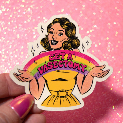 A die-cut sticker featuring a retro-style cartoon woman with wavy brown hair, a yellow dress, and a rainbow with the text 'GET A VASECTOMY', held by a hand against a pink glittery background.