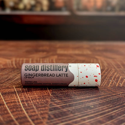 Lip balm with 'Soap Distillery' branding on a wooden surface, Gingerbread Latte Lip Balm