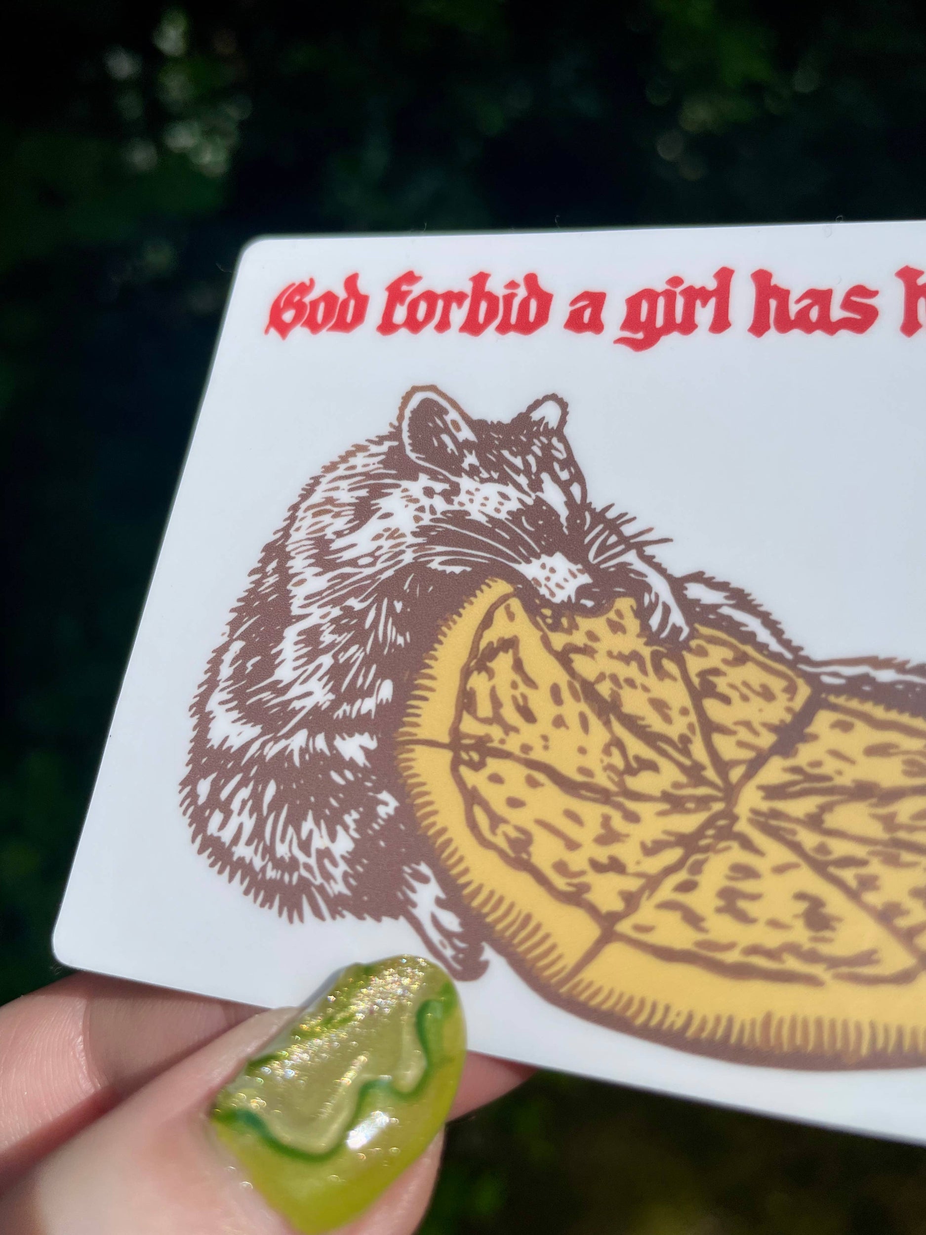 Card with a rat and pie illustration and text held by a hand with green nail polish.
