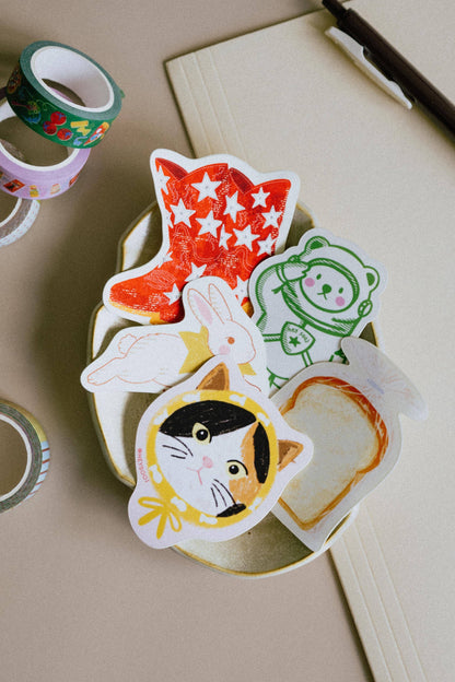 Set of colorful animal-themed stickers on a beige surface with tape and paper in the background.