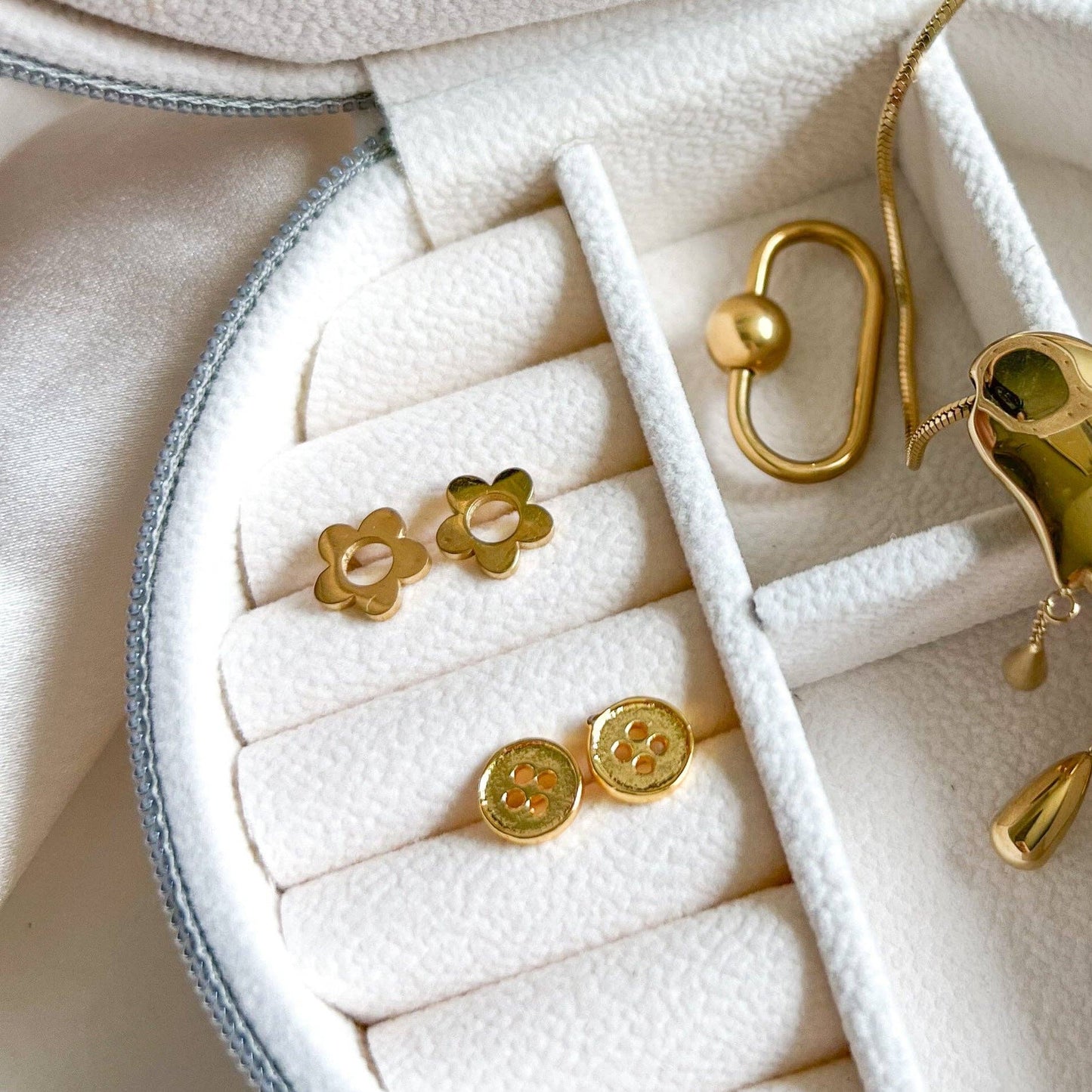 Gold earrings displayed in a jewelry box on a white surface