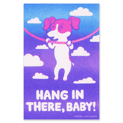 A risograph art print featuring a stylized white dog with pink ears and paws hanging from a pink rope against a blue-to-purple sky with white clouds. The text at the bottom reads “HANG IN THERE, BABY!” with the artist name “Sionan Gallagher” below.