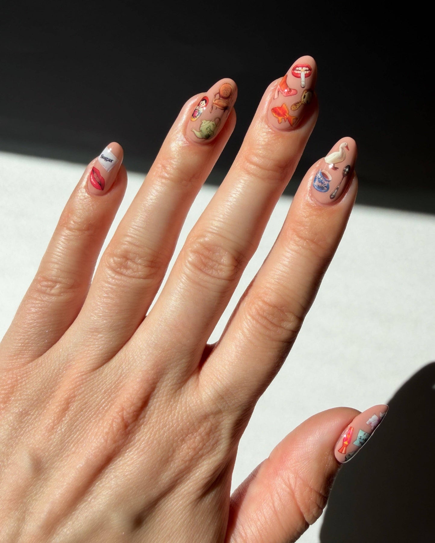 Close-up of a hand with intricately designed nails on a neutral background