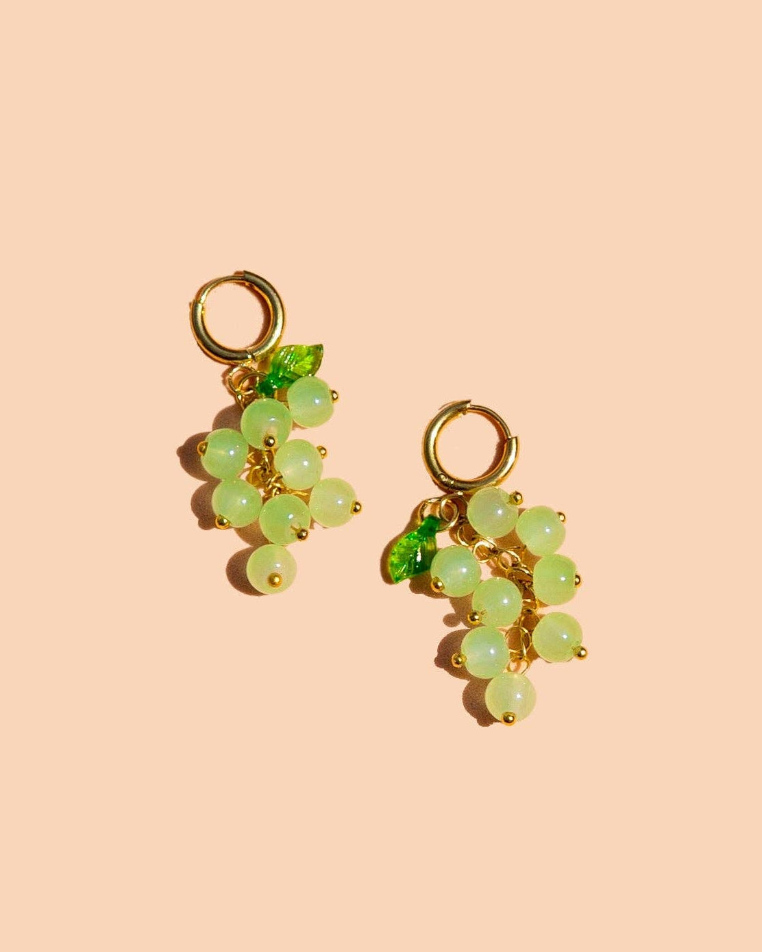 Pair of green grape-shaped earrings on a beige background, Heard It Through The Grapevine Hoop Earrings