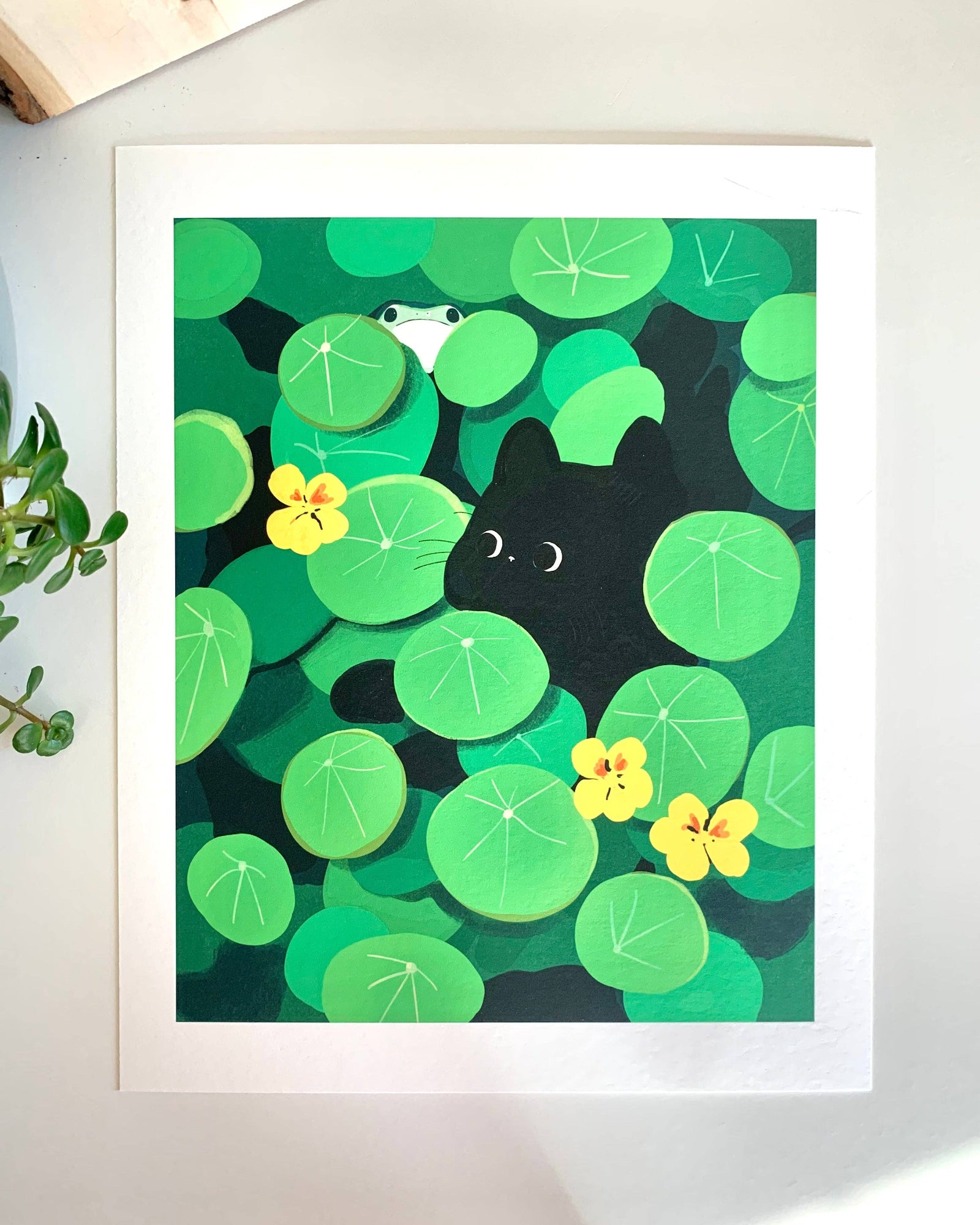 artwork of a black cat and a frog among green leaves and yellow flowers on a white background, Hide and Seek Cat Art Print