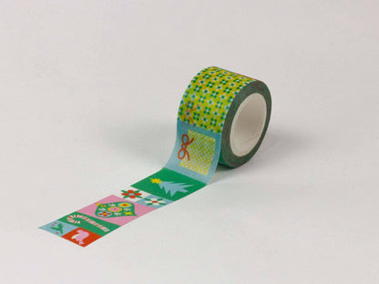 A roll of decorative washi tape with a green and yellow checkered pattern and a strip unrolled showing festive Christmas designs, photographed on a light gray background.