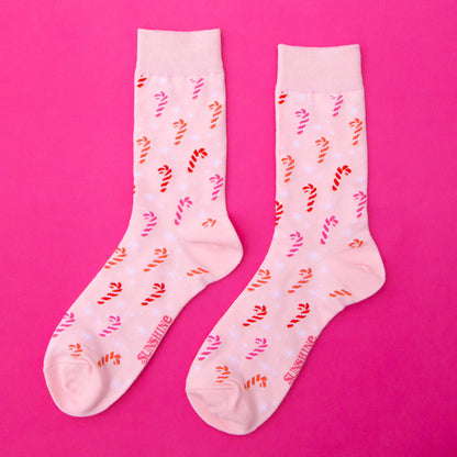 Pair of socks with candy cane pattern on a pink background