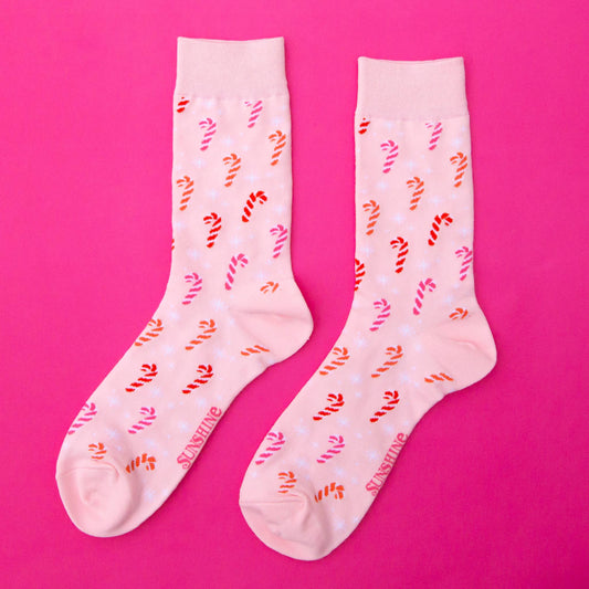 Pair of socks with candy cane pattern on a pink background