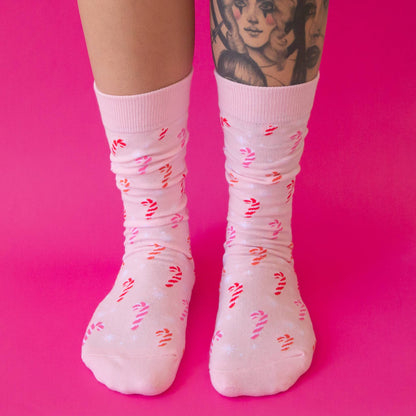 White socks with pink and red patterns worn by a person on a pink background