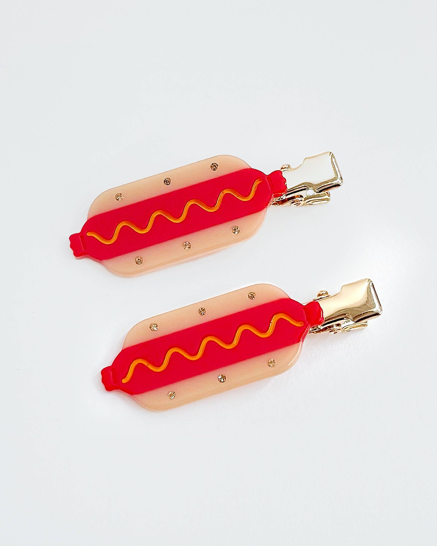 Two hot dog-shaped hair clips on a white background