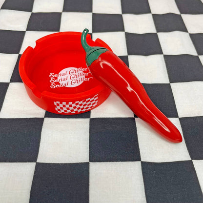 Red pepper-shaped bottle opener with 'Serial Chiller' text on a checkered background
