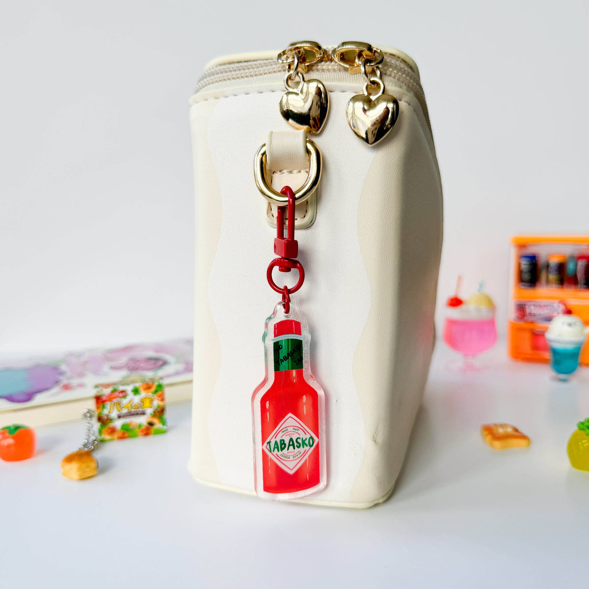 White pouch with a Tabasco bottle keychain on a white background