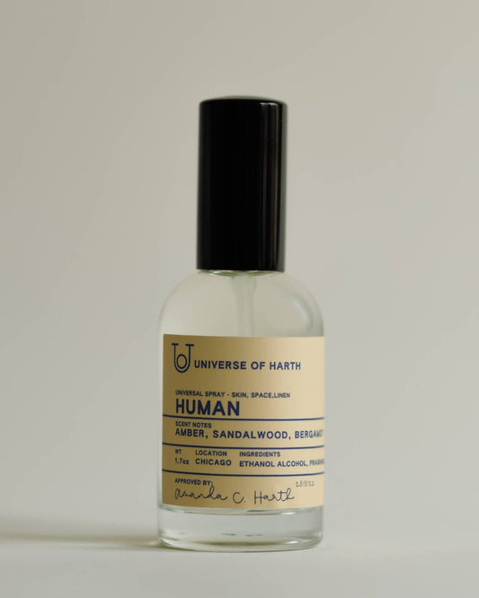 Small glass bottle with a black cap on a light gray background, Human: Room, Space and Body Spray