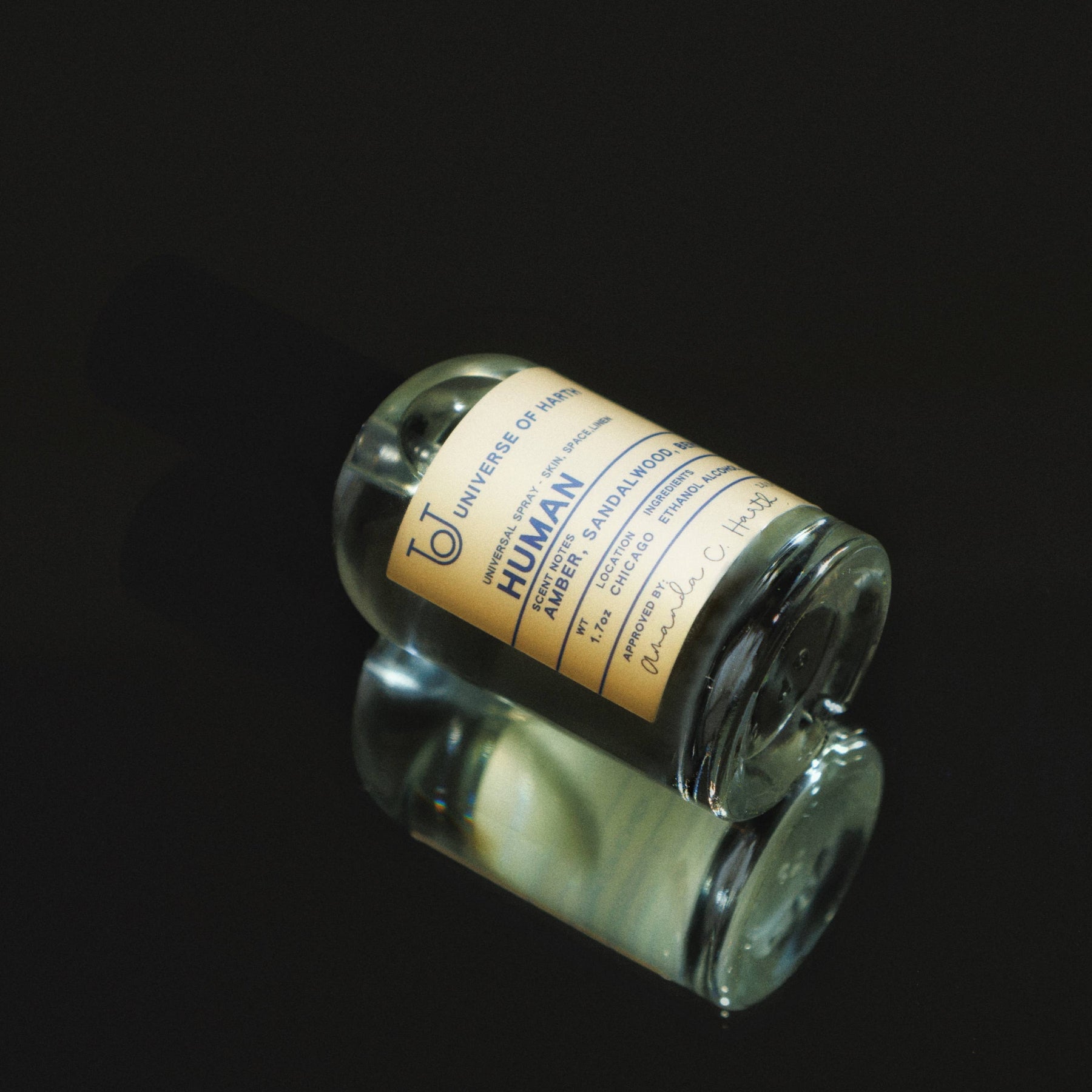 Small glass bottle with a yellow label on a black background, Human: Room, Space and Body Spray