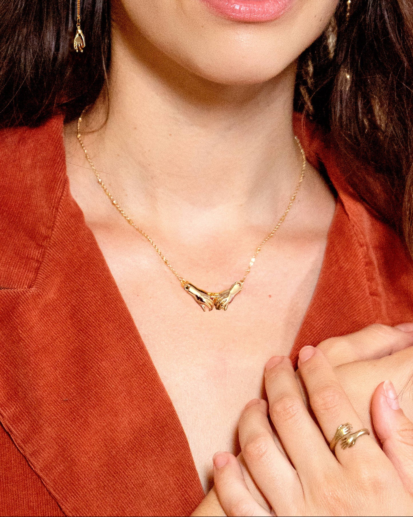 Close-up of a woman wearing gold jewelry including earrings, necklace, and ring.