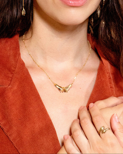 Close-up of a woman wearing gold jewelry including earrings, necklace, and ring.
