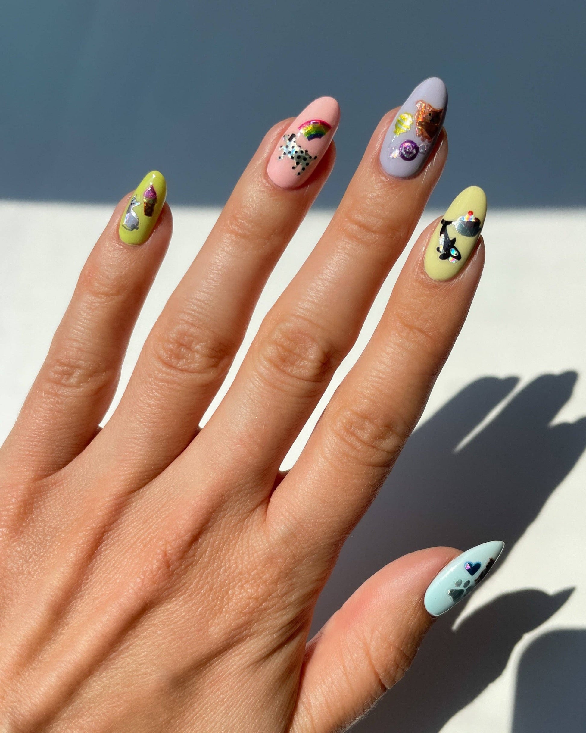 Hand with colorful nail art against a neutral background