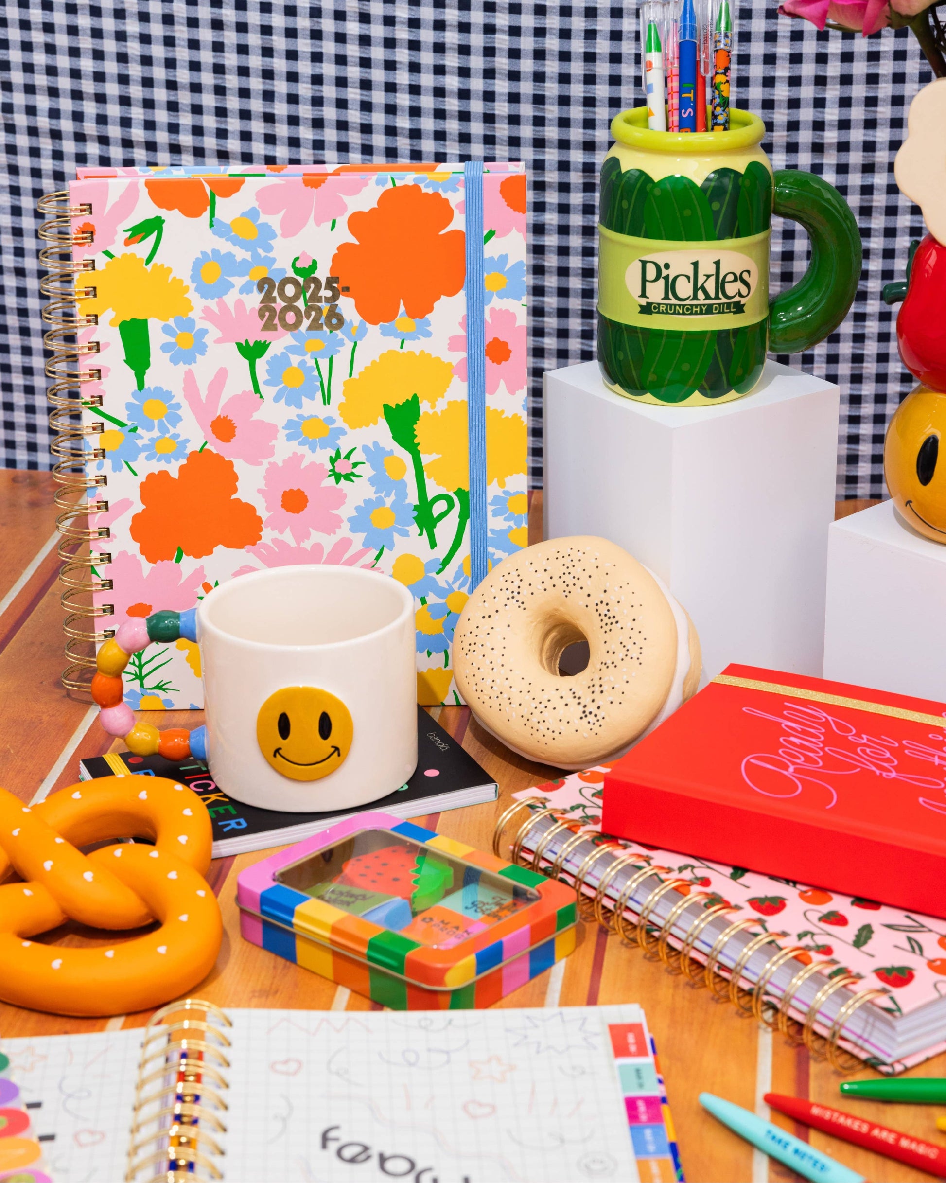 Colorful stationery items including a mug, notebook, and donut on a checkered background