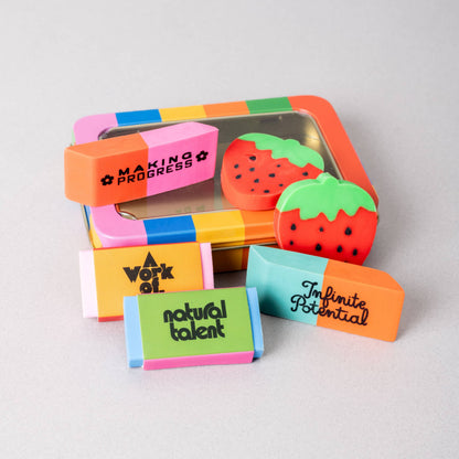 Colorful strawberry-shaped erasers with motivational phrases on a light gray background