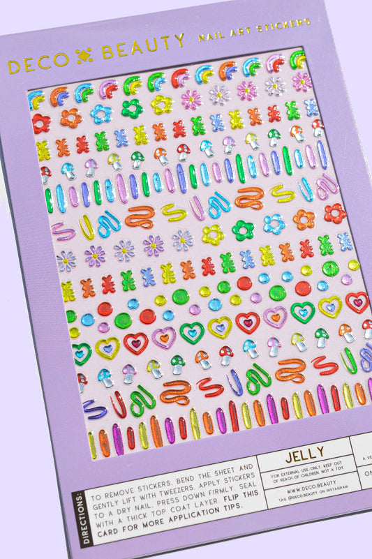 A sheet of colorful nail art stickers from Deco Beauty, featuring various floral, heart, and barrette designs in bright pastel and neon colors, shown on a lavender background.