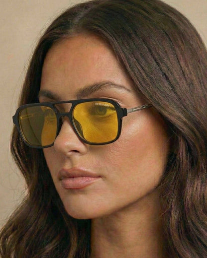 Woman wearing sunglasses with yellow lenses against a neutral background