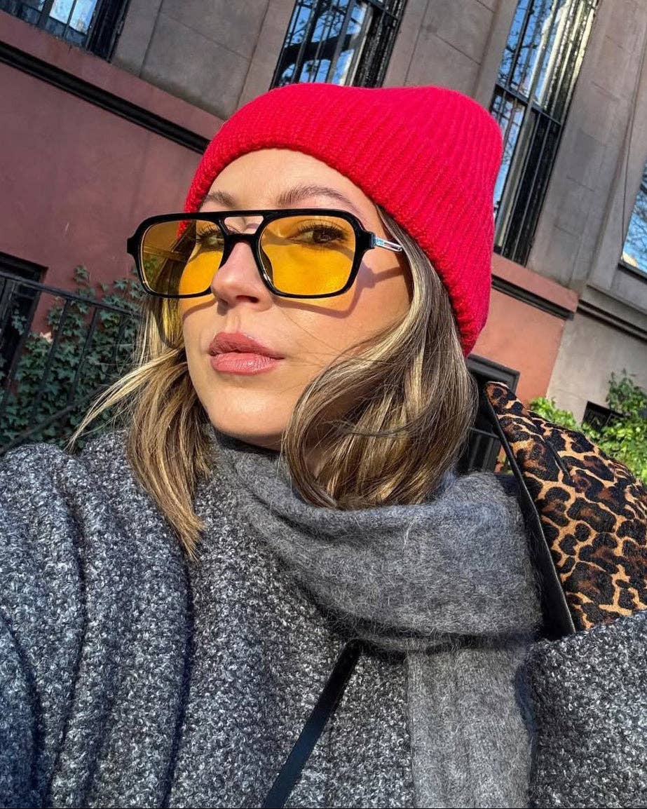 Person wearing a red beanie and yellow sunglasses outdoors