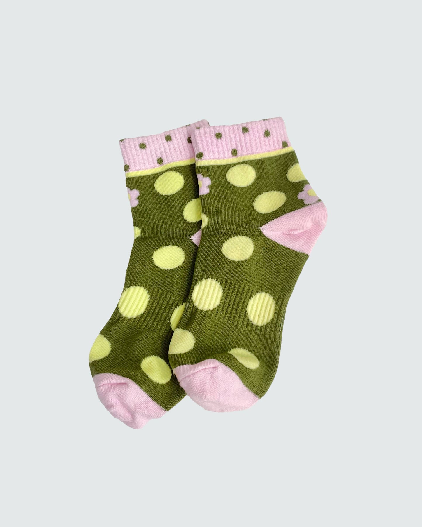 Green socks with yellow polka dots and pink accents on a light gray background