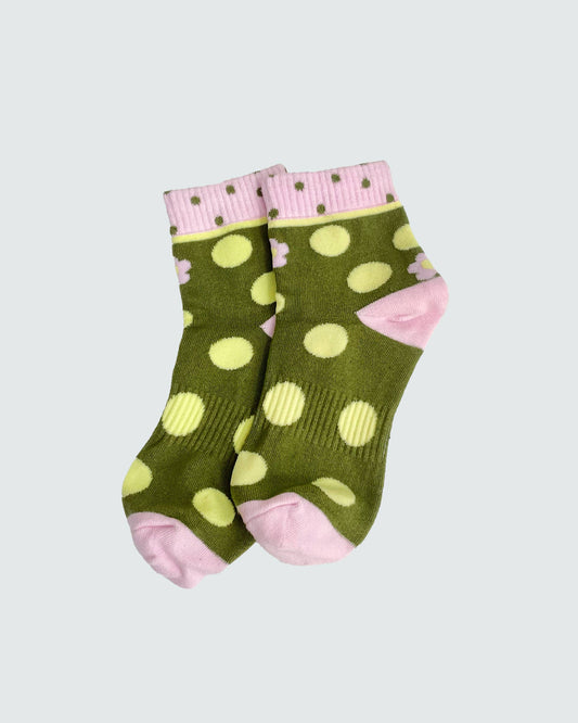 Green socks with yellow polka dots and pink accents on a light gray background